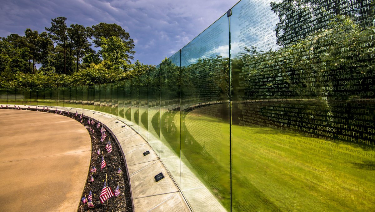 Wall memorializing veterans with American flags on ground in front