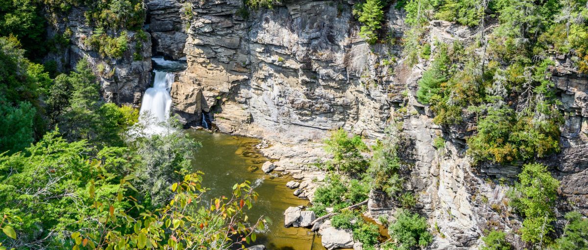 Aerial view of Linville Falls surrounding by rocks, cliffs and green trees during daytime