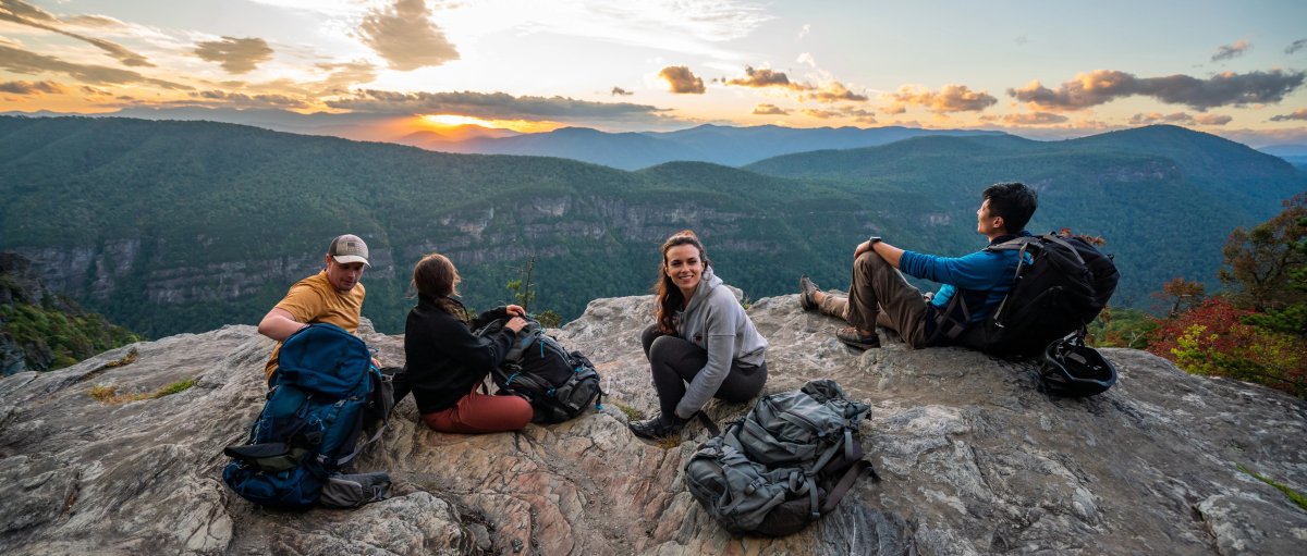 Friends sitting on rock watching sunset in the distance