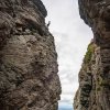 Person rock climbing on side of cliff with mountains in distance