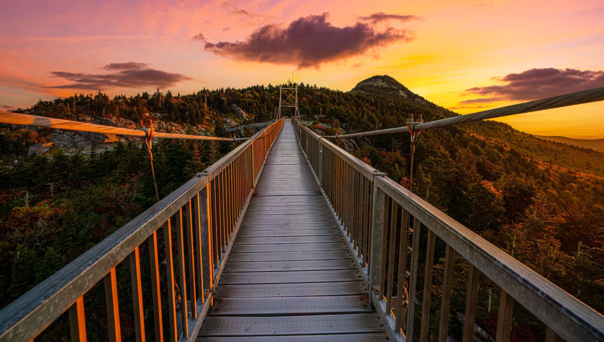 Mile High Swinging Bridge walkway surrounded by fall foliage and brilliant pink sky