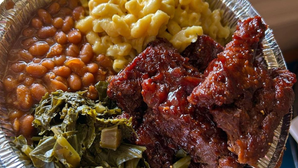 Closeup of to-go dish of vegan ribs, mac n cheese, and collards