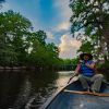 Man paddling a canoe on a river in Lumberton during daytime