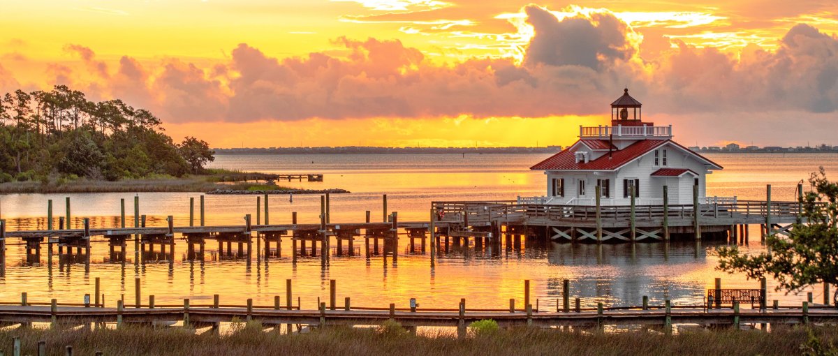 Roanoke Marshes lighthouse with orange and yellow sky in background