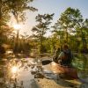 Couple canoeing through Merchants Millpond State Park with sun streaming through trees