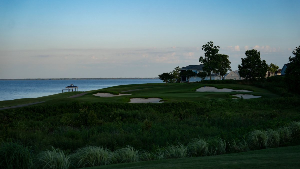 Waterfront golf course's bunkers, sand trips and greens surrounded by plants and trees