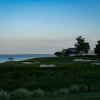 Waterfront golf course's bunkers, sand trips and greens surrounded by plants and trees