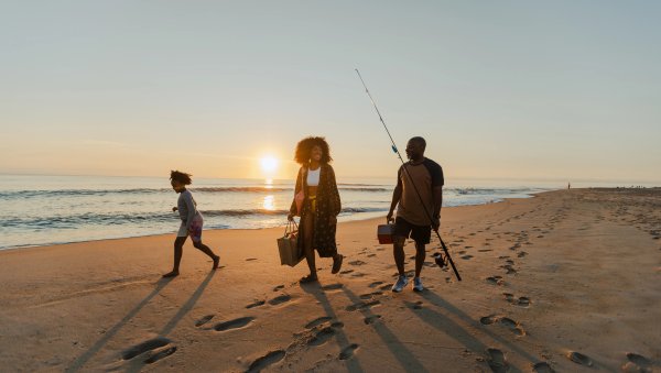 Mother and her father talking and walking while daughter runs ahead of them on the beach. Taken at sunset in the Outer Banks.