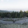 Person walking dog on paved trail with trees and mountain vistas in backbround