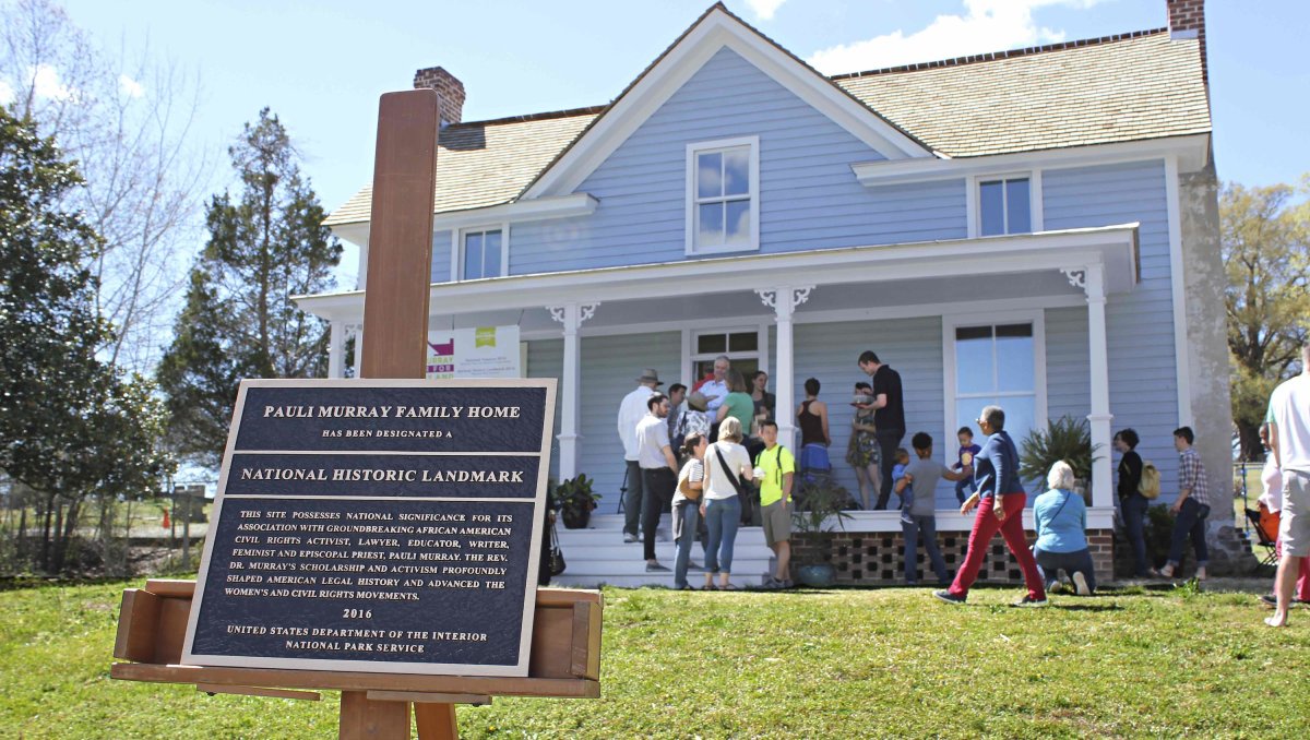 People standing on porch of Pauli Murray Family home with signage in foreground