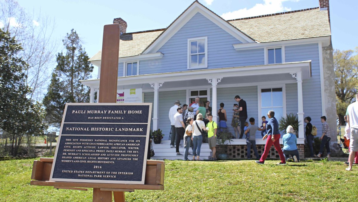 People standing on porch of Pauli Murray Family home with signage in foreground