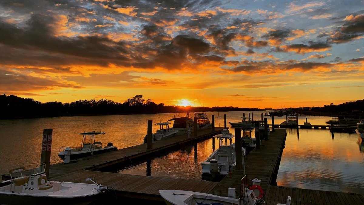 Sun setting over waterway with boats at docks