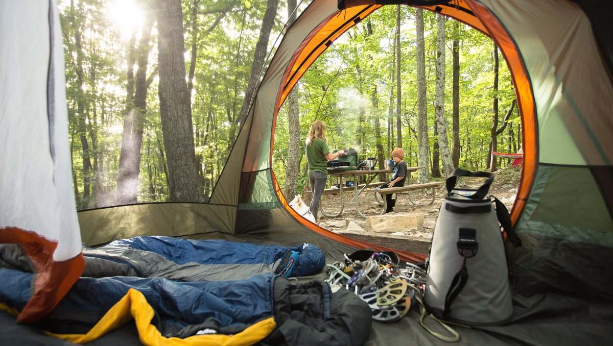 Inside tent looking outside onto campsite where mom and son stand