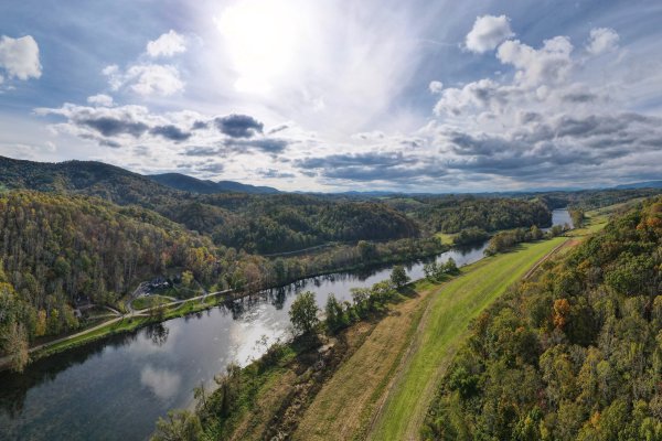 Aerial of New River surrounded by fall foliage and mountains during daytime