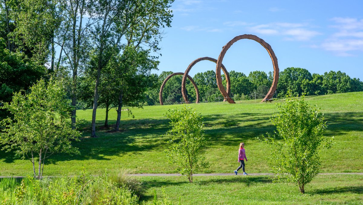 Woman walking on path in the outdoor Museum Park at North Carolina Museum of Art on sunny day