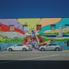 Bright music mural on entire side of building with cars parked next to building