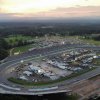 Aerial view of NASCAR track with people in stands and mountains in background