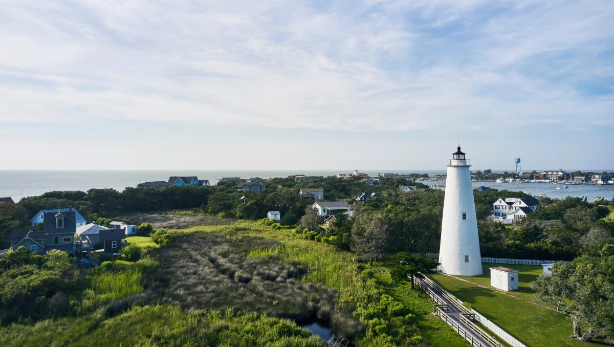 Aerial view of Ocracoke Lighthouse and green marshes and houses surrounding it