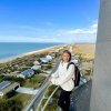 Woman smiling at camera while standing at top of lighthouse during daytime