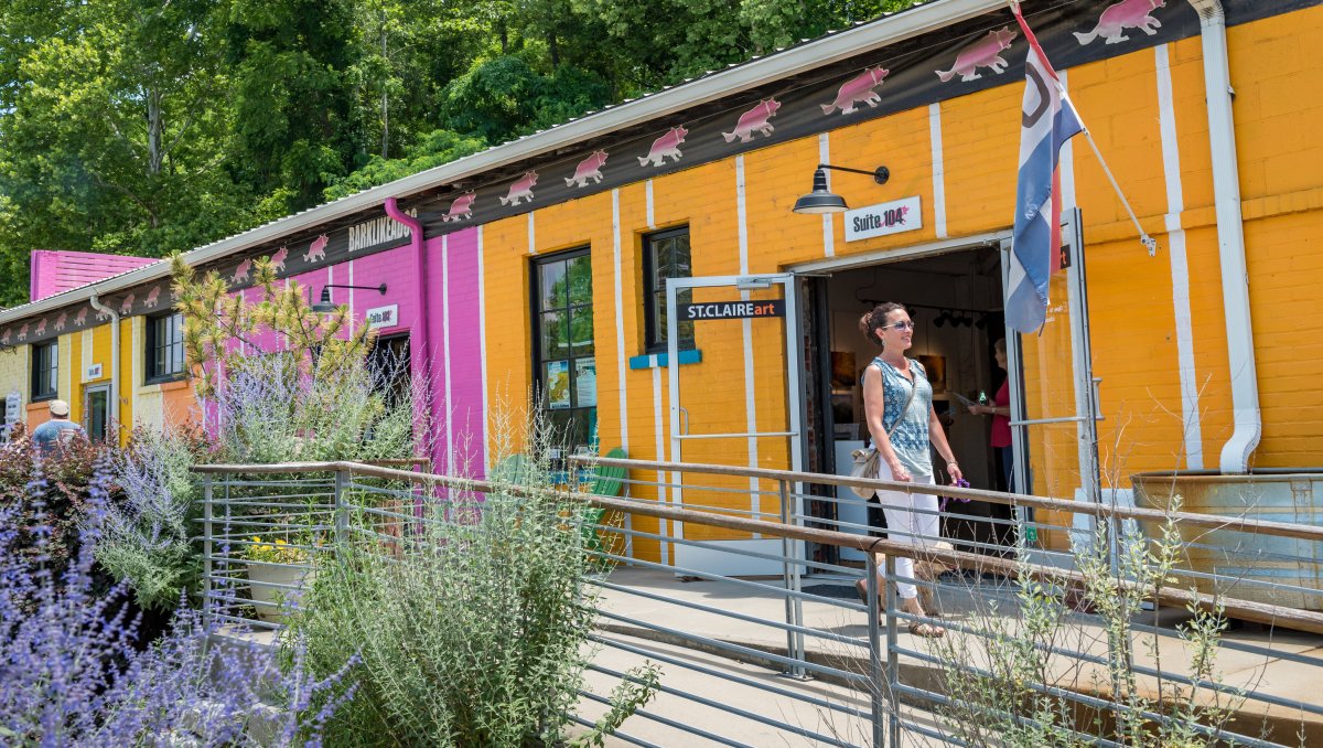 Woman walking in front of colorful art galleries in Asheville