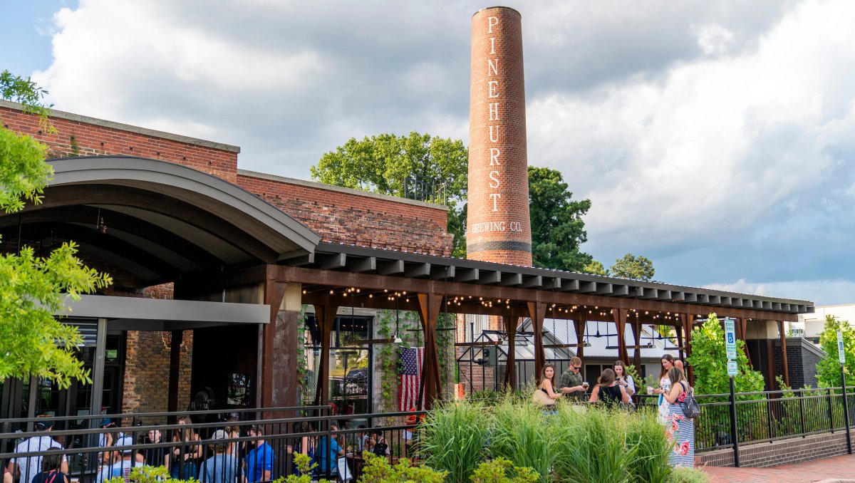 Exterior of brewery with industrial feel and people standing outside