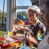 Person sitting at table about to bite into seafood sandwich with plate of food in front