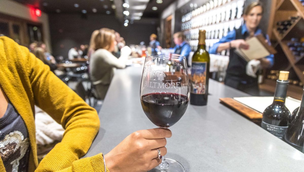 Woman holding glass of wine while she sits at bar at Biltmore Winery