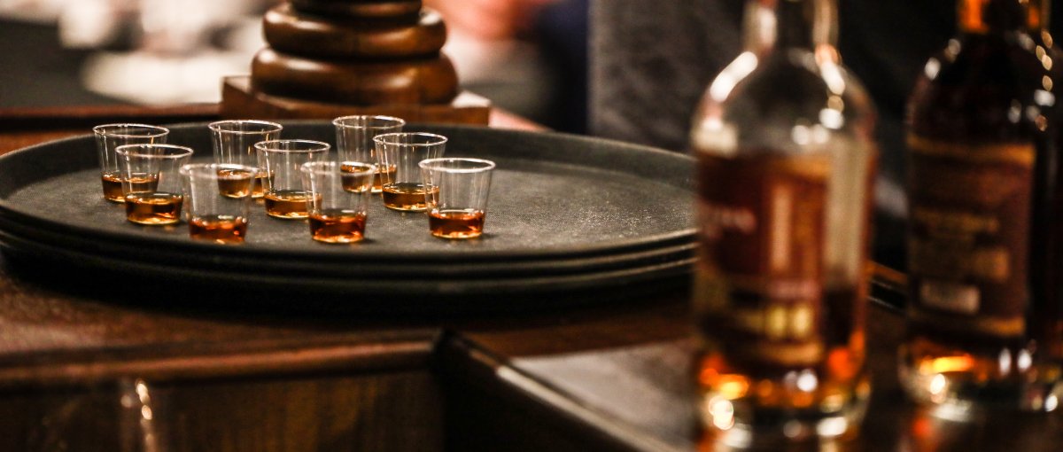 Tray of whiskey shots with out of focus bottles in foreground