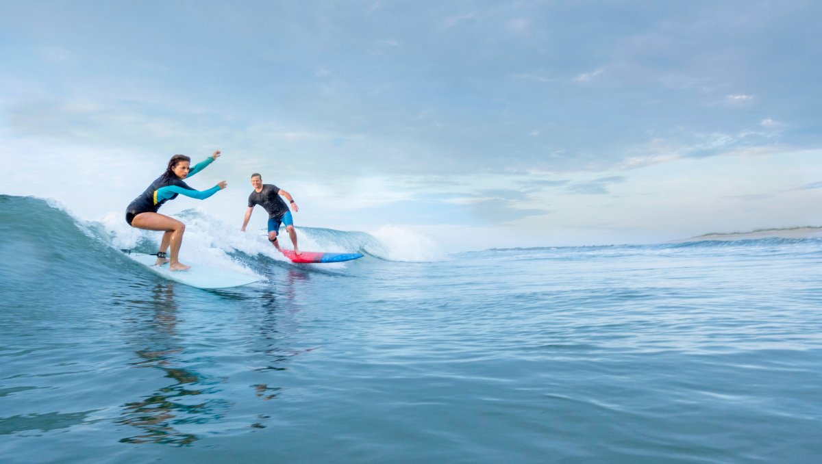 Two surfers catching a wave in Wrightsville Beach on bright day