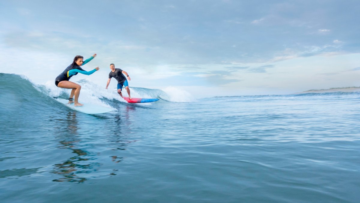 Two surfers catching a wave in Wrightsville Beach on bright day