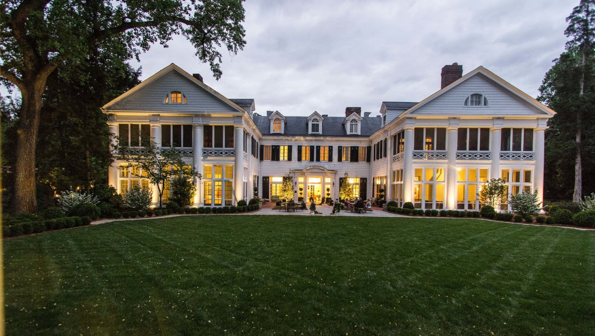 Exterior of Duke Mansion at dusk with lower level let up and grassy grounds in foreground