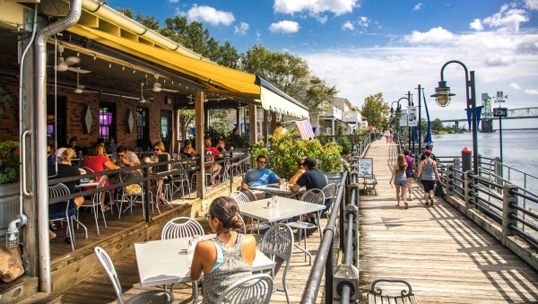 Diners sitting outside alongside Wilmington Riverwalk during daytime