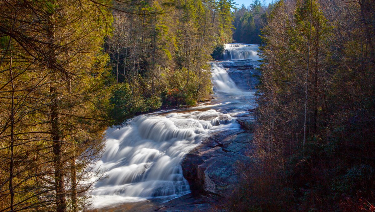 Three-tiered waterfall in middle of forest surrounded by fall foliage