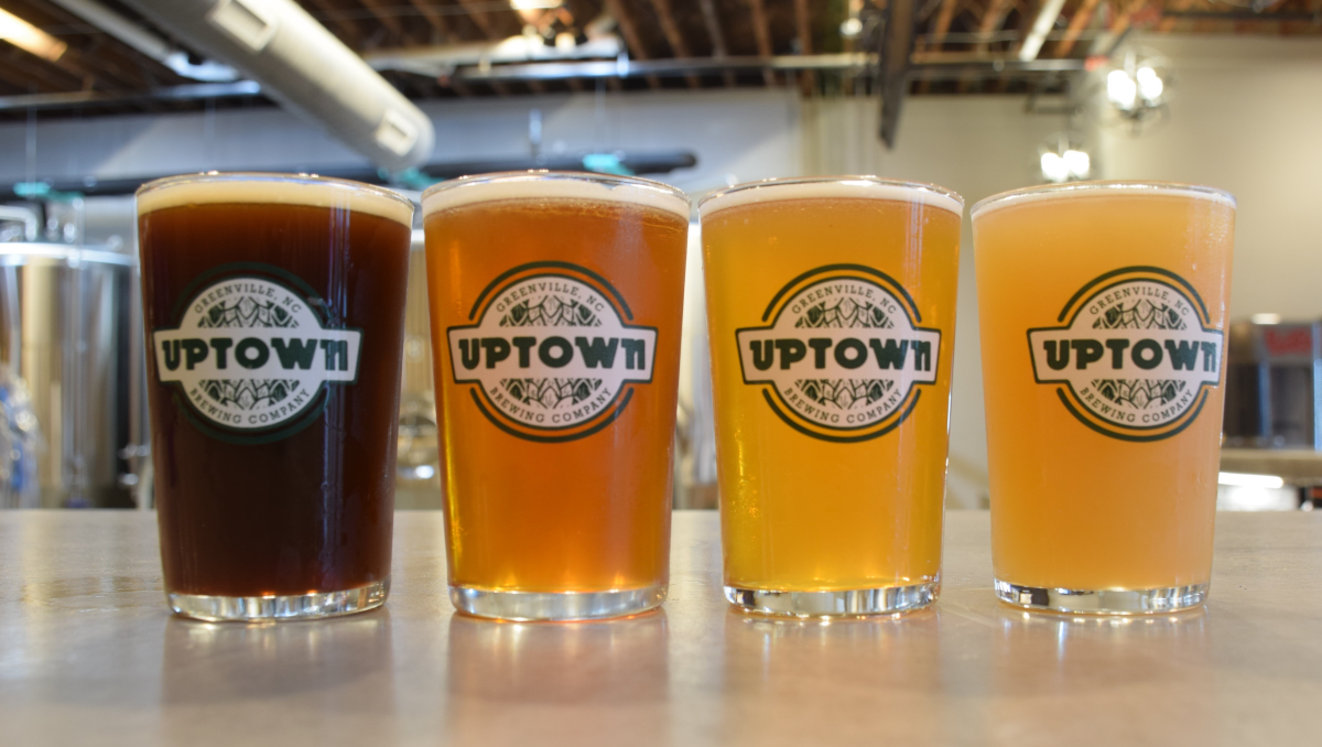 Flight of four beers sitting on counter with brewery in background