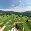 Aerial view of green golf course with mountains in distance during daytime