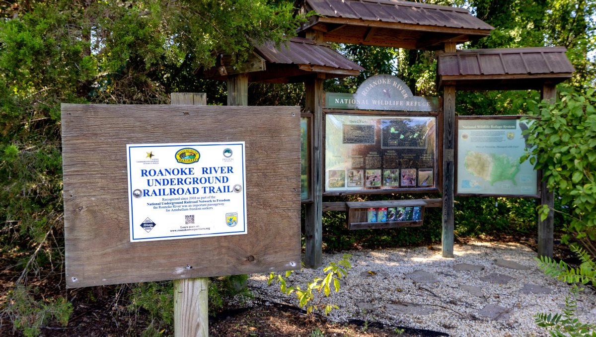 Trail and informational signage in wildlife refuge in front of trees