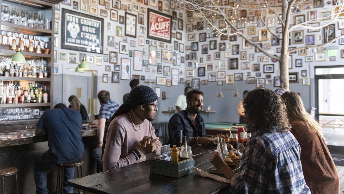 Four friends enjoying lunch in quirky restaurant with indoor tree in bar area